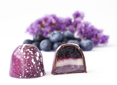 Chocolate candy in a cut on a white background. Blueberry and lavender flavor and taste. Blurred ingredients on background